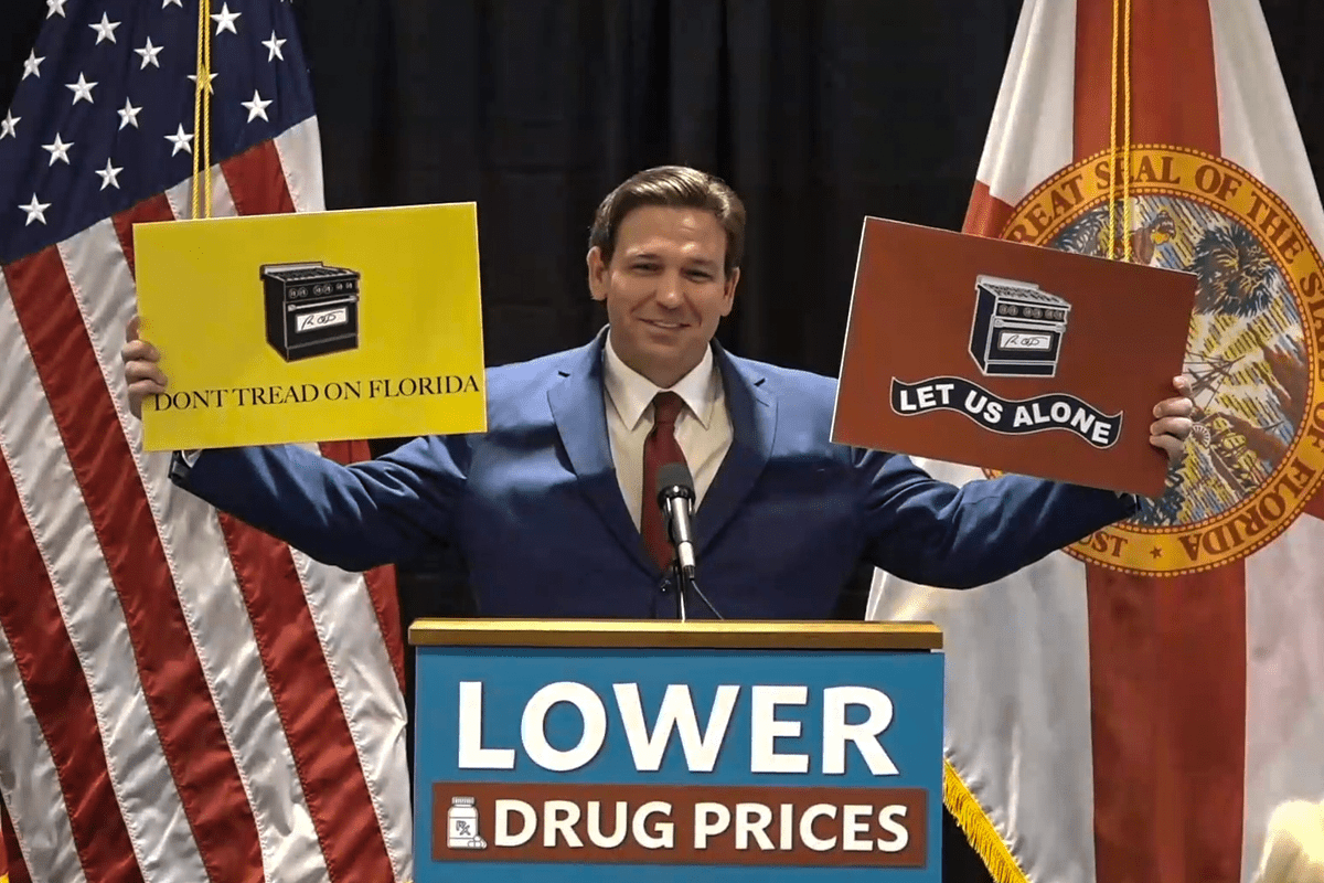 Gov. Ron DeSantis holds up "Don't Tread on Florida" and "Let Us Alone" gas stove signs at a press conference, The Villages, Florida, Jan. 12, 2023.